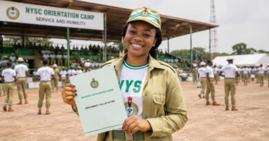 An NYSC corps member in uniform at an orientation camp discussing Place of Primary Assignment (PPA) placements.